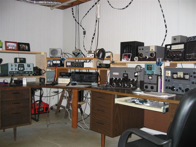 Fred's shack . L-shaped with HW-100 on the left and and old VIking 2, Hammarlund receiver, and Drake 2-B receiver.